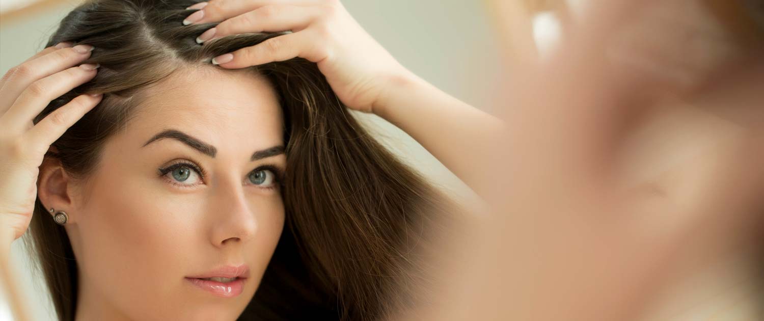 Woman looking at her hair line in a mirror.